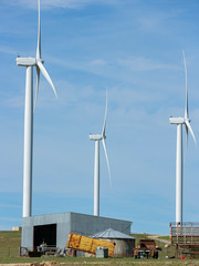 Wall Mural - three large wind turbines moving to create kinetic energy for renewable energy supply with a farm sh