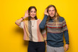© luismolinero - Hippie couple over yellow background listening to something by putting hand on the ear