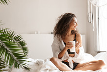 Image Of Beautiful Young Woman Drinking Tea On Bed In White Apartment