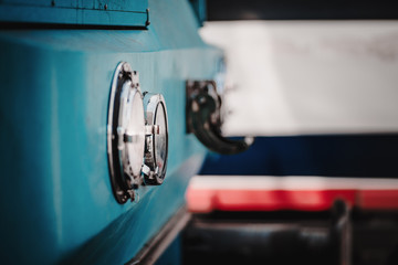 Close-up view with selective focus on one of two chrome headlamps of a modern railroad locomotive waiting on maintenance on a railway track, shallow depth of field, a copy space place on the right