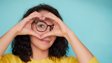 Woman In Glasses On A Turquoise Background Makes A Heart Shape With Her Hands, A Symbol Of Love