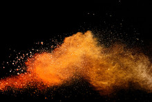 Abstract Orange Powder Explosion Isolated On Black Background.