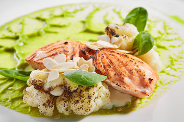 Sticker - Salmon steak on plate closeup. Red fish piece with green pea puree and cauliflower. Salmon with creamy sauce and vegetables isolated on white background. Restaurant tasty dish, cooked healthy meal