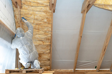 Wall Mural - Professional foreman installing thermal insulation rock wool under the roof