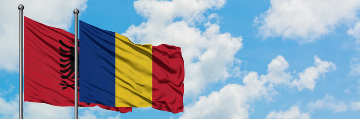 Albania and Romania flag waving in the wind against white cloudy blue sky together. Diplomacy concept, international relations.