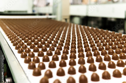 chocolate toppings on the conveyor of a confectionery factory close-up