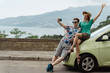© Arsenii - Young man and woman taking selfie on smartphone while travel by car