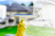 Window cleaner for washing a windows. Hand in yellow glove hold cleaning squeegee.
