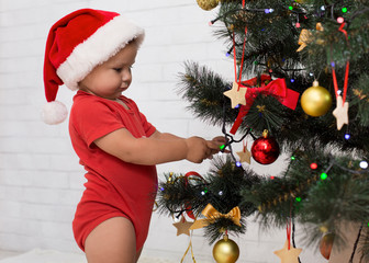 Wall Mural - Adorable baby hanging red ball on Xmas tree