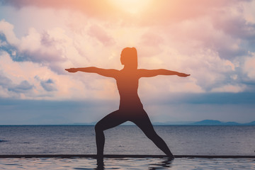 Wall Mural - silhouette Athletic woman practice yoga Warrior one pose to meditation summer vacation on pier with sunset sea beach,Travel in tropical beach Thailand,vacations and relaxation Concept