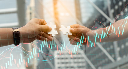 Teamwork,partnership and Social connection in business join hand together concept.Businessman holding jigsaw puzzle with chart.Financial Graph. Stock Market chart.