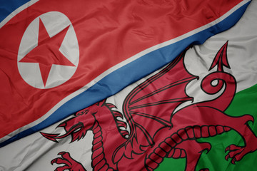 waving colorful flag of wales and national flag of north korea.