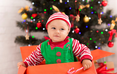 Wall Mural - Curious baby searching Christmas presents in big box under Xmas tree