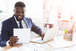 © Prostock-studio - Satisfied black businessman checking documents, sitting in modern office