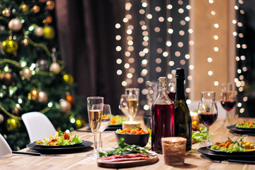 Wall Mural - Festive table setting. Food and drinks, plates and glasses. Evening lights and candles. New Year's Eve.