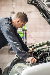 Wall Mural - Car mechanic repairer service technician checks and repairs auto engine