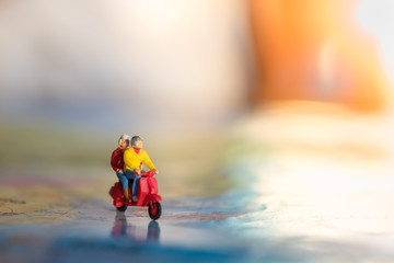 travel concept. close up of two traveler miniature figure ride motocycle / scooter on world map with