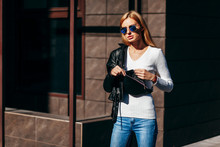 Stylish Model Girl At The City In Black Leather Jacket And White Sweater And Glasses With Waist Bag