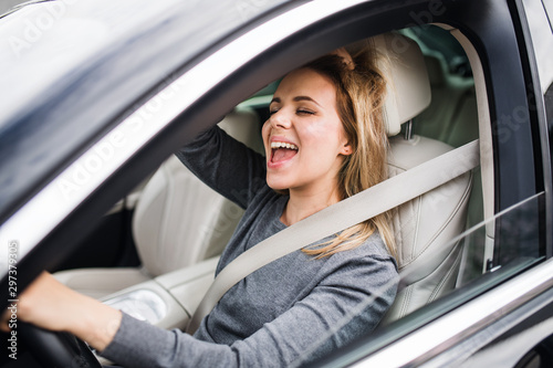 Cuadros en Lienzo Cheerful young woman driver sitting in car, driving.