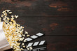 © Nikolay N. Antonov - Cinema concept. Popcorn in a box and movie clapper on wooden background top view. Free space.