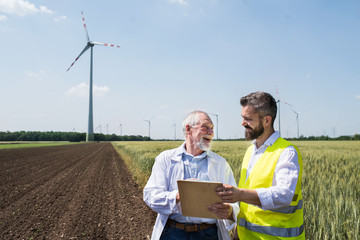 Wall Mural - Engineers standing on wind farm, making notes.