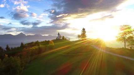 Wall Mural - aerial view of landscape of church of st. primoz near jamnik, slovenia and julian alps at background