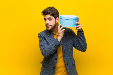 young handsome man  with a box against orange background