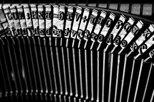 Glossy font on a small typewriter. Close-up of parts and letters in a typewriter.