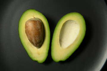 Fresh, raw avocado sliced on a black plate