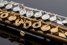 Two Shiny Gold And Silver Plated Flutes On A Reflective Surface. An Instrument Common In A Symphony Orchestra