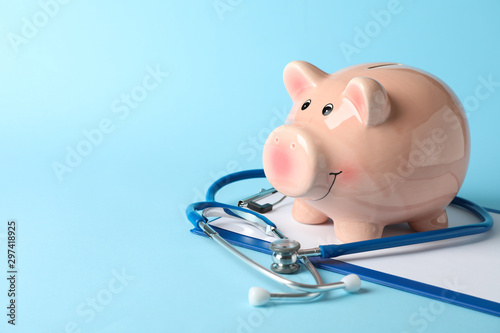 Cuadros en Lienzo Stethoscope and piggy bank on blue background, space for text