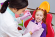 © Evgeniy Kalinovskiy - children's dentist examines the teeth and mouth of the child - a cute red-haired girl sitting in a dental chair. Pediatric dentistry