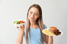Woman With Healthy And Unhealthy Food On Light Background. Diet Concept