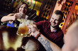© Evgeniy Kalinovskiy - a group of friends - young guys and girls drinking beer, talking and smiling at the bar