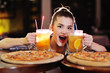 © Evgeniy Kalinovskiy - a young pretty girl eating pizza and drinking beer or a beer citrus cocktail on the background of a bar or pizzeria.