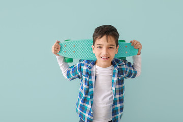 Wall Mural - Cute fashionable boy with skateboard on color background