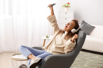 Wall Mural - Beautiful African-American woman listening to music at home