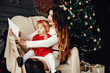 © hetmanstock2 - Elegant mother in a white sweater. Family with letter. Little girl near christmas tree