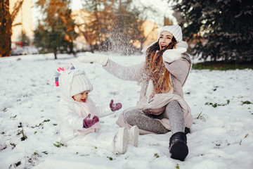 Family have fun in a winter park. Stylish mother in a pink jacket. Little girl in a winter clothes.