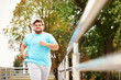 © New Africa - Young overweight man running outdoors. Fitness lifestyle