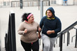 © New Africa - Overweight couple running up stairs together outdoors