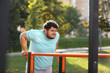 © New Africa - Young overweight man training on sports ground