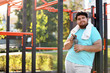 © New Africa - Young overweight man with bottle and towel on sports ground