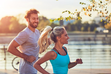 Modern woman and man jogging / exercising in urban surroundings near the river.