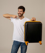 © SB Arts Media - Stylish handsome man showing suitcase. Advertising storage space for travelers and tourism image.