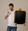 © SB Arts Media - Stylish handsome man showing suitcase. Advertising storage space for travelers and tourism image.