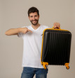 © SB Arts Media - Stylish handsome man showing suitcase. Advertising storage space for travelers and tourism image.