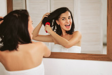 Beautiful Happy Woman Brushing Healthy Hair In Front Of The Mirror. Girl Combing Her Hair And Fools Around