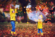 © Olesia Bilkei - happy excited kids having fun, throwing leaves in autumn park, wearing rain boots and coats