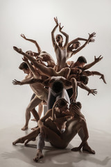 Wall Mural - The group of modern ballet dancers. Contemporary art ballet. Young flexible athletic men and women in ballet tights. Studio shot isolated on white background. Negative space.